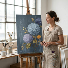 Umelkyňa v Papilora ateliéri stojí vedľa dreveného stojana s hotovým obrazom hortenzie, prirodzené denné svetlo z veľkého okna.